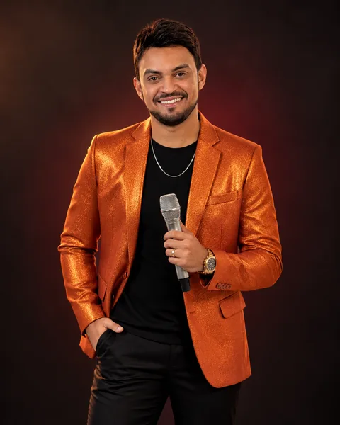 Peagá — microfone, blazer cobre e luz âmbar
